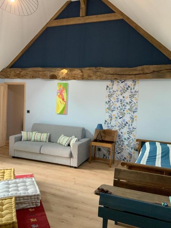 Grand dortoir sous la charpente avec canapé, lits et jeux